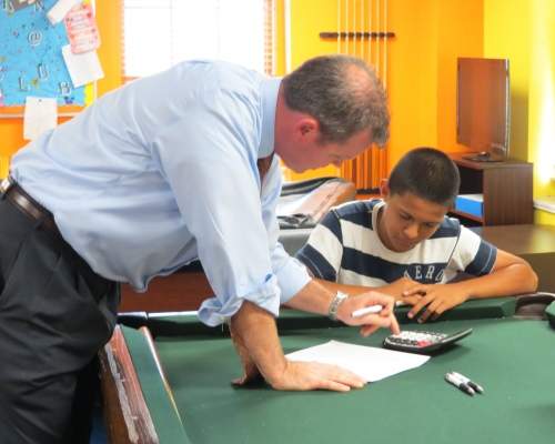 Young boy at calculator and teacher