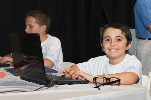 Young boy smiling in front of laptop
