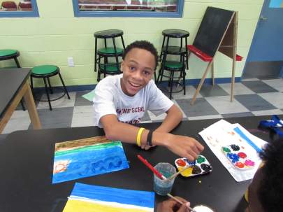 Young boy smiling while painting