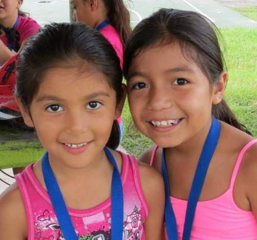 Two young ladies wearing pink smiling.